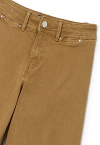 Jeans de mezclilla de algodón marrón con corte recto, que cuentan con bolsillos frontales, cremallera en la bragueta y herrajes decorativos en plata.