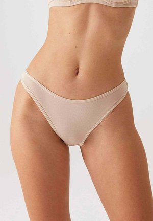 Beige geribbelde bikini-slipjes met een dunne tailleband. Gladde textuur; minimale bedekking met een gebogen vorm. Geen zichtbare patronen of hardware.