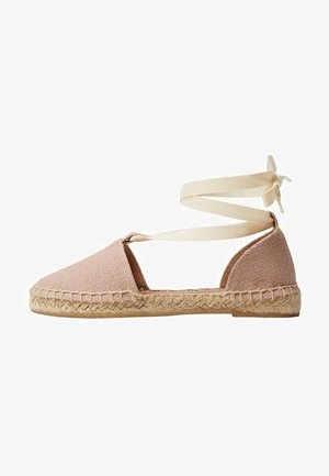 Espadrille plate rose clair avec semelle en jute tissée et lien de cheville crème, bout arrondi fermé et côtés ouverts.