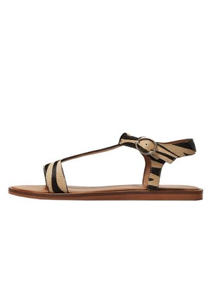 Flad sandal med brun sål, brune og sorte zebra-mønstrede remme og en rund sølvspænde på ankelstroppen.