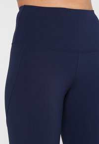 Marinblå kompressionsleggings med hög midja, mjuk textur och inga synliga sömmar eller utsmyckningar. Designade för komfort och flexibilitet.