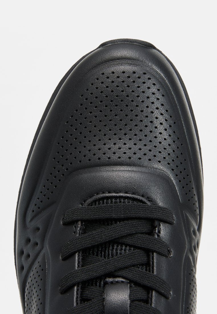 Baskets de sport noires avec une tige synthétique perforée, des panneaux texturés, un bout rond et des lacets plats. Présente un design élégant et épuré.