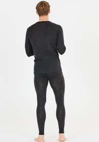 Donkere grijze blouse met lange mouwen en bijpassende leggings, gemaakt van een zachte, gestructureerde stof met een slim fit, gezien vanuit de achterkant.