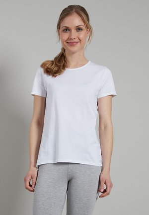 White cotton t-shirt with short sleeves and a round neckline, featuring a relaxed fit and smooth texture. Worn with grey leggings.