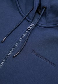 Felpa con cappuccio blu navy, dotata di zip centrale, lacci e logo ricamato "PeakPerformance". Tessuto in cotone misto morbido, design informale.