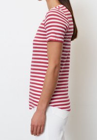 Rød og hvid stribet T-shirt, kortærmet, blødt stof, rund halsudskæring, lidt længere bageste søm, båret med hvide bukser.