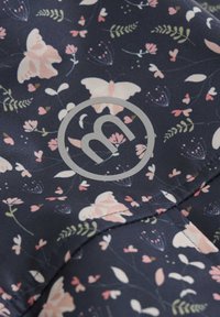 Marineblauter Stoff mit einem floralen Muster aus pinken Blumen und Schmetterlingen. Ein graues rundes Logo mit dem Buchstaben "m" ist prominent dargestellt.