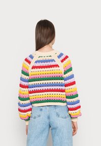Wielokolorowy sweter dzianinowy o luźnym kroju, z poziomymi paskami w kolorach czerwonym, żółtym, zielonym, niebieskim i różowym. Żebrowane mankiety i dekolt.