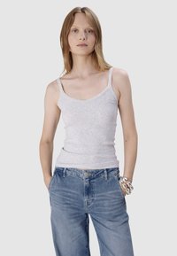 Szary prążkowany top bez rękawów z cienkimi ramiączkami, z delikatnie fakturowanej tkaniny. W zestawieniu z jasnoniebieskimi dżinsami i srebrną bransoletką.