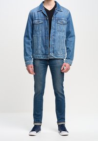 Džínová bunda s bledě modrým washed efektem, dvěma náprsními kapsami, zapínáním na knoflíky a volným střihem, ve spojení s tmavě modrými džíny a námořnickými teniskami.