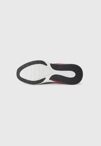 Semelle de chaussure de sport avec un extérieur en caoutchouc noir, un intermédiaire blanc et des motifs de semelle texturés pour l'adhérence. Présente un accent rouge sur le côté.