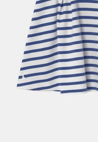 Tessuto a righe blu e bianche con una leggera piega, caratterizzato da un piccolo logo ricamato in basso. Design pulito e semplice.