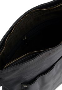 Sort lædertaske med en glat tekstur, der har en lynlåslomme, mørk stofoverflade og en frontlomme.