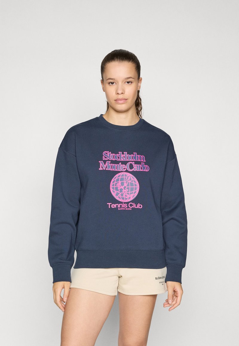Navy blue sweatshirt featuring a pink graphic print with "Stockholm Monte Carlo Tennis Club" and globe design. Cotton material, relaxed fit.