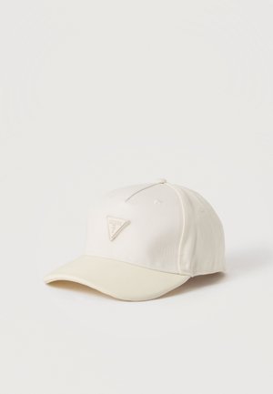 Casquette de baseball blanche avec une visière incurvée et un patch triangulaire du logo Guess à l'avant, présentée sur un fond clair uni.
