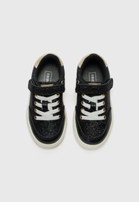 Sneaker nere glitterate con colletto imbottito, lacci bianchi, occhielli dorati e cinturino in velcro. Suola in gomma con un accento beige a contrasto.