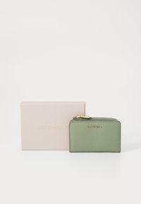 Green textured leather wallet with gold hardware, zip closure, and embossed logo. It is displayed next to a light pink box.