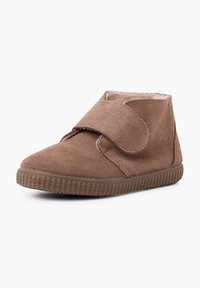 Stivale alla caviglia in suede marrone con strappo in velcro, suola in gomma, punta rotonda e rivestimento interno morbido. Caratterizzato da una texture liscia e design semplice.