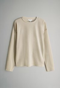 Beige langærmet skjorte med ribbet tekstur, rund halsudskæring og afslappet pasform. Har sænkede skuldre og lige kant.