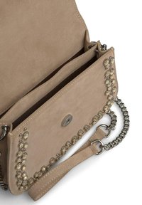 Beżowa torebka z zamszu z akcentami w srebrnym kolorze, z klapką i łańcuszkowym paskiem. Wnętrze posiada dwa przedziały do przechowywania.