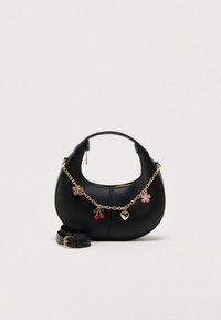 Sac à main en cuir noir à la forme incurvée, avec une bandoulière chaîne dorée et des breloques décoratives comprenant un papillon, des cerises et une fleur.