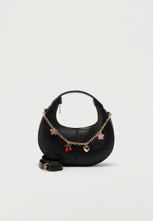 Sac à main en cuir noir à la forme incurvée, avec une bandoulière chaîne dorée et des breloques décoratives comprenant un papillon, des cerises et une fleur.