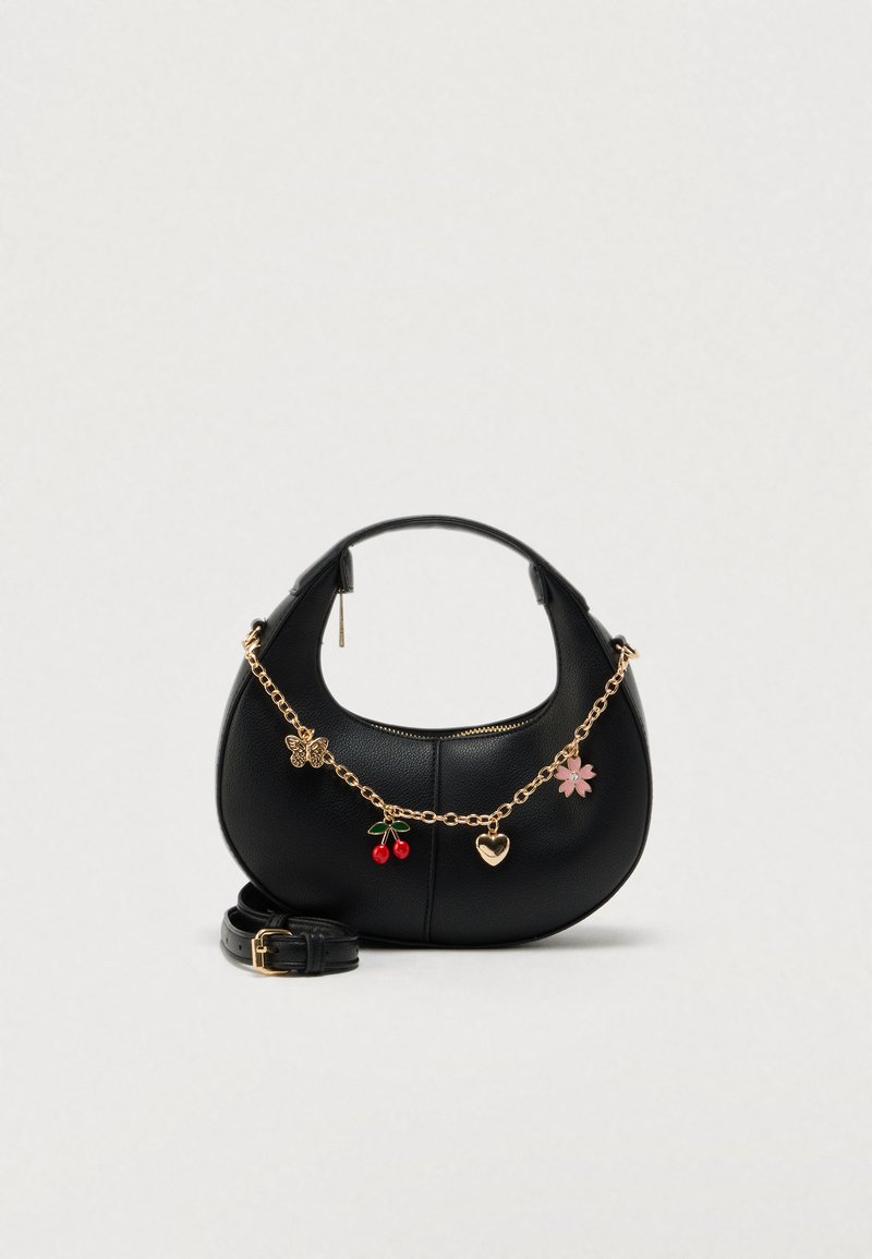 Sac à main en cuir noir à la forme incurvée, avec une bandoulière chaîne dorée et des breloques décoratives comprenant un papillon, des cerises et une fleur.