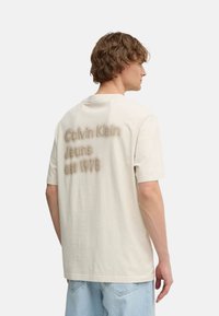 Camiseta de algodón beige con la inscripción "Calvin Klein Jeans est 1978" en texto tonal en la parte posterior. Fit relajado, con mangas cortas y escote redondo.