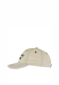 Beige baseballcap med grønne øjer og syede detaljer. Har en buet skygge og tekst på forsiden. Lavet af bomuldsstof.