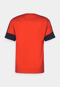 Röd t-shirt med rund hals och korta ärmar; marinblå detaljer vid ärmsluten; slät textur; enkel design; inga mönster eller grafik.