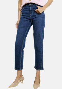 Tumed sinised denim teksad sirge lõikega, kõrge vöökoha ja lühikese pikkusega, millel on vööaasad ja nähtavad õmbluse detailid.