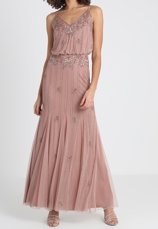 Blush pink evening gown with a v-neck, embellished bodice, layered skirt, and floral bead accents, featuring thin spaghetti straps and flowy texture.