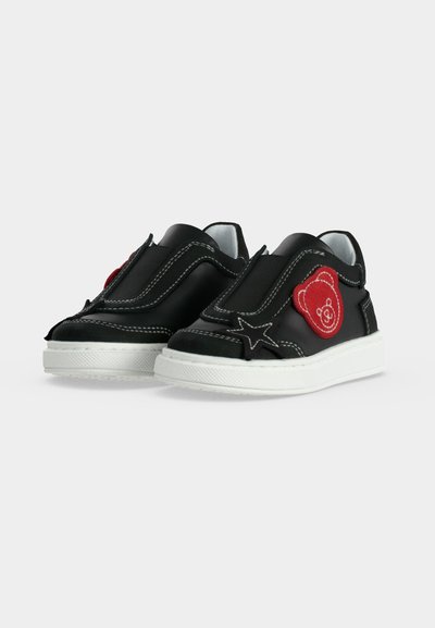 Μαύρα παιδικά sneakers χωρίς κορδόνια με λευκές σόλες, κόκκινο σχέδιο αρκούδας στο πλάι και λευκές ραφές σε απλό φόντο.