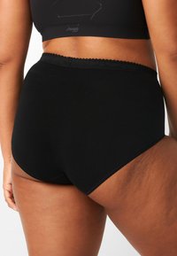 Slip neri in cotone a vita alta con una fascia decorativa a onda. Texture liscia e senza motivi o accenti visibili.