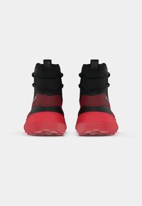 Schwarze und rote Sportschuhe mit hoher Knöchelunterstützung, strukturiertem Mesh-Obermaterial, auffälliger roter Gummimittelsohle und kontrastierendem Profil.