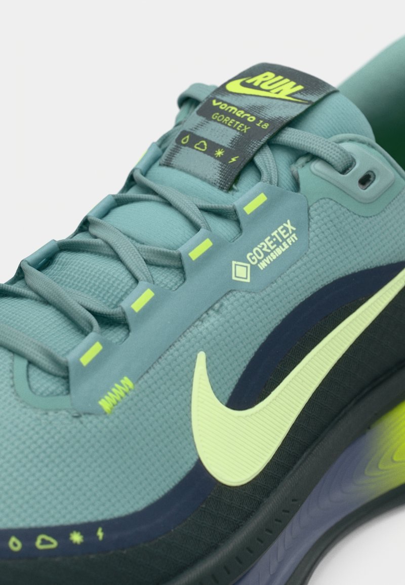Die GORE-TEX Nike Vomero 18 Schuhe verfügen über ein strukturiertes Obermaterial in Teal, neonfarbene Akzente und eine schwarze Sohle mit Farbverlauf-Details.