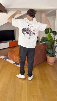 Valkoinen t-paita, jossa on graafinen kuvasto, jossa on cowboy hevosen selässä ja teksti "Rodeo". Mustat housut, joissa on hienovarainen kuvio. Valkoiset lenkkarit.