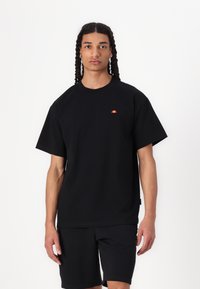Black short-sleeve t-shirt made of cotton, featuring a small red and orange logo on the left chest area, paired with black shorts.