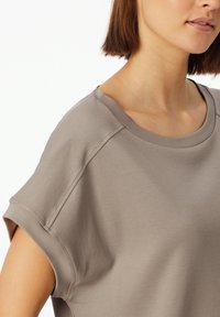 Lichte taupe kortemouwen T-shirt van zachte stof, met een ronde halslijn en een losse pasvorm, voorzien van subtiele stikdetails.