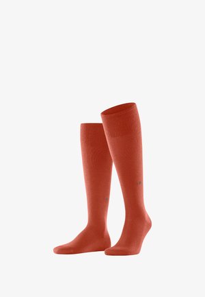Chaussettes corail montantes, affichées à la verticale, présentant une texture lisse et un logo discret près de la cheville.