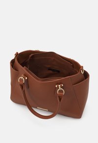 Bruine synthetische handtas met gouden hardware, dubbele ronde handvatten en ritssluiting. Bevat binnenvakken en heeft een gladde textuur.