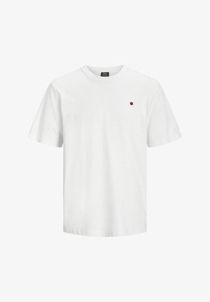 Fehér pamut póló, kerek nyakkal, rövid ujjakkal, és egy kis piros ponttal a bal mellrészen. Sima textúrájú és laza szabású.