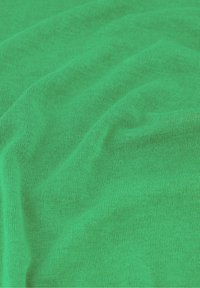 Groene katoenen stof met zichtbare brei-textuur en natuurlijke plooien, die een zachte, licht gekreukte materiaall surface toont.