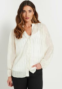 Weißes Button-up-Bluse aus transparenter, texturierter Stoff mit vertikalen metallischen Streifen. Hat lange Ärmel und eine lockere Passform.