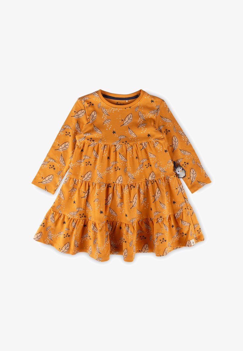 Langärmliges Kleid in Senfgelb, mit geschichteten Rüschen, die ein Blatt- und Sternmuster zeigen, und einem kleinen dekorativen Patch am Ärmel.