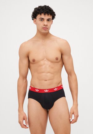 Schwarze Baumwollslips mit rotem Bund, der weiße Logoakzente aufweist. Enganliegende Passform, glatte Textur und klassisches Slip-Design.