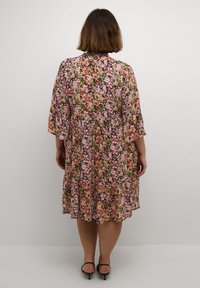 Robe fleurie avec un motif vibrant aux teintes rose, verte et jaune. Coupe ample, manches trois-quarts et ourlet au genou.