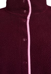 Burgundi värvi fliisjakki, millel on kõrge kaelus, roosa ääris ja läikivad tumepunased nupud esiküljel. Pehme, tekstuuriga kangas.