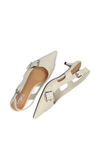 Witte pumps met een spitse neus, open zijkanten en zilverkleurige gespsluitingen. Gemaakt van glad synthetisch materiaal met een slank hakontwerp.