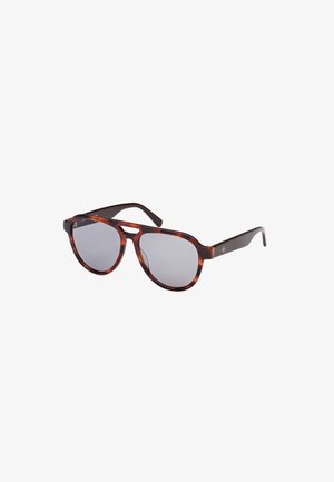 Gafas de sol de carey con lentes redondeados y tinte gris. Están hechas de plástico con brazos delgados oscuros, y cuentan con acentos de logo en los laterales.